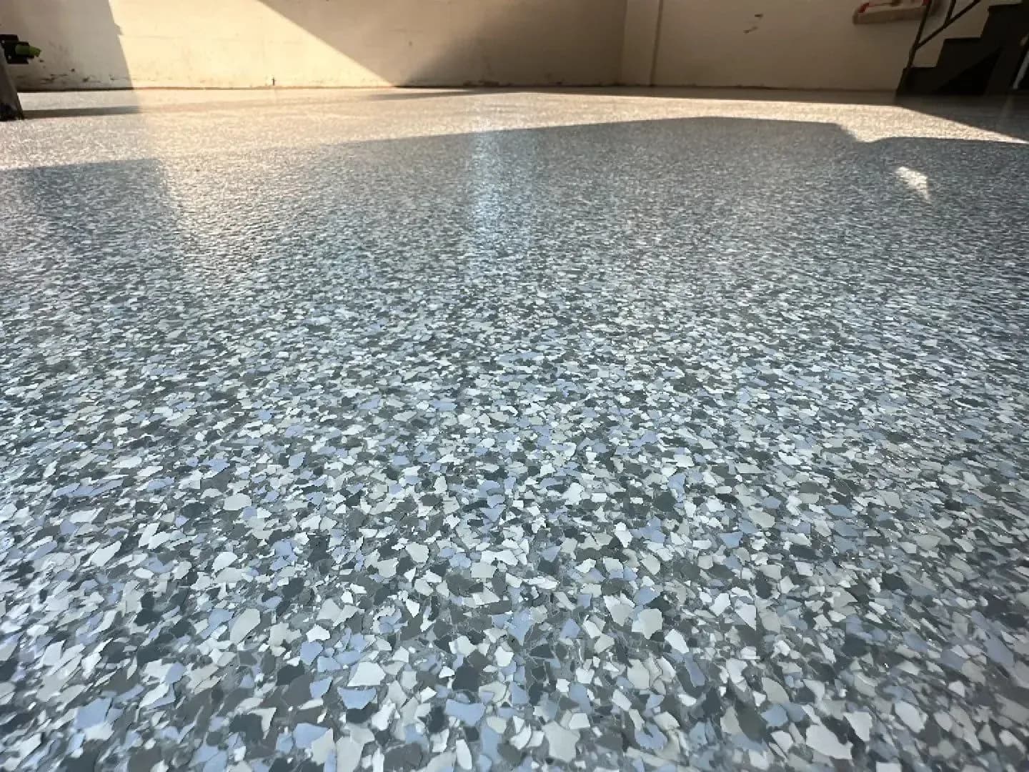 Polished concrete floor with gray and white speckled aggregate finish in an indoor space with white walls and natural light